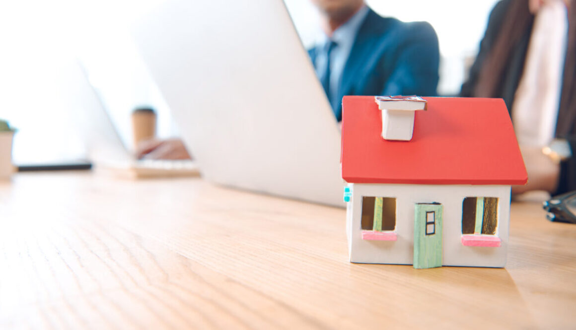 partial view of insurance agents at workplace with house model in office, house insurance concept