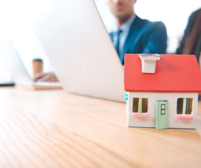 partial view of insurance agents at workplace with house model in office, house insurance concept